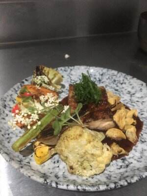 Grilled chicken teriyaki with sauted mix vegetable garlic butter and tare fermented sauce, garnish by adible flower, garlic chips