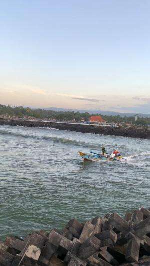 melihat perahu nelayan melewati ombak muara cikidang